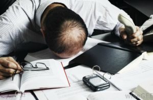 Man with Head on Desk in Frustration
